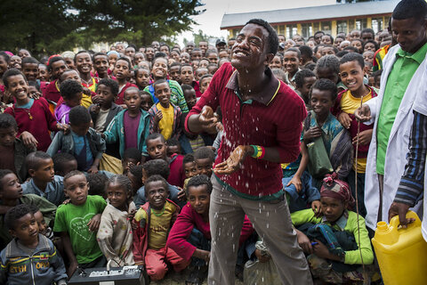 Shelmel Terefa, a school teacher, demonstrates face washing to students at his school in Aware-Golje village in the North Shewa Zone, Oromia, Ethiopia. (Photo credit: Michael Amendolia/The Fred Hollows Foundation.)