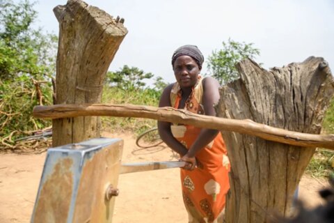 Prossy, a member of the Buwaiswa community in Uganda, pumps the borehole to obtain water for her family.