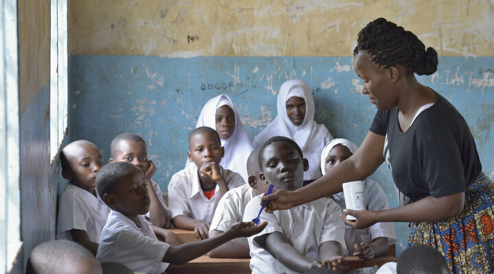 Enetia Madembo distributes pills in a public school in Vikuge, Tanzania, during mass drug administration through the USAID ENVISION project. The pills include Praziquantel and Albendazole. (Photo by Paul Jeffrey for IMA World Health)